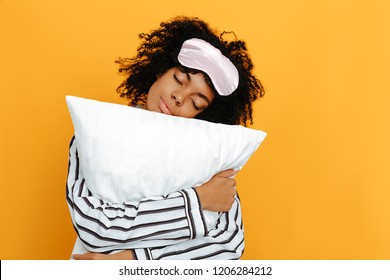 Sleeping. Dreams. Woman Portrait. Afro American Girl In Pajama Is Hugging A Pillow, On A Yellow Background