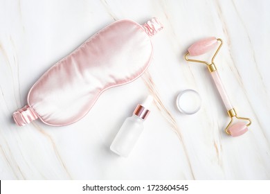 Sleeping eye mask, serum dropper bottle, moisturizer cream, face massage roller on marble background. Nighttime skincare routine concept - Shutterstock ID 1723604545
