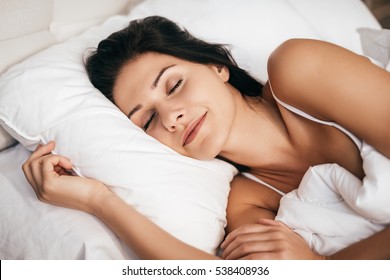 Sleeping At Home. Beautiful Young Woman Smiling During Sleeping While Lying In The Bed At Home 