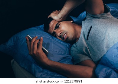 Sleeping Man Being Woken Up By Mobile Phone In Bedroom At Night