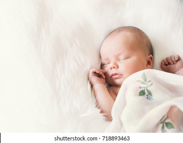Sleeping newborn baby in a wrap on white blanket. Beautiful portrait of little child girl 7 days, one week old. - Shutterstock ID 718893463
