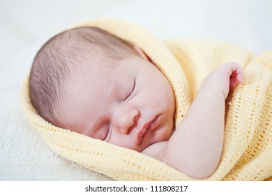 Sleeping Newborn Baby Wrapped In A Yellow Blanket