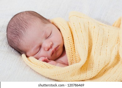 Sleeping Newborn Baby Wrapped In A Yellow Blanket