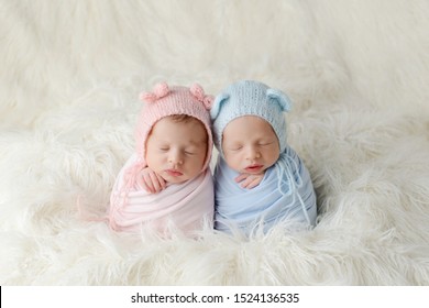 The sleeping Newborn girl and boy lies on the white fur. Newborn twins