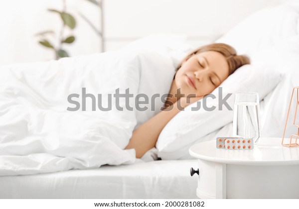 Sleeping pills\
on table in bedroom of young\
woman
