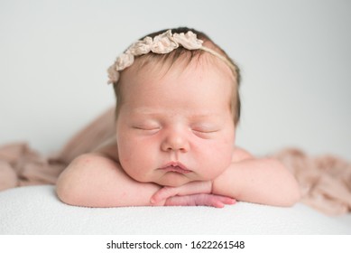 A sleeping, three week old, newborn baby boy swaddled in a gauzy blue wrap. Shot in the studio on a white blanket.
