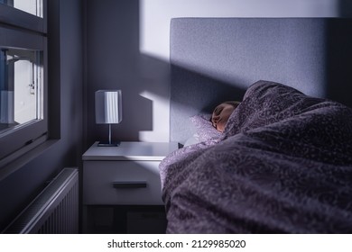 Sleeping Woman In Bed At Night In Dark Bedroom. Person Resting. Asleep Under Cover And Blanket. Cold Room At Home. Tired Lady In Peaceful Dream. Blue Moonlight From Window. Sick With Flu.