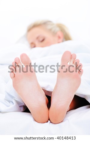 Sleeping woman with a clean  feet protruding from under the bedspread