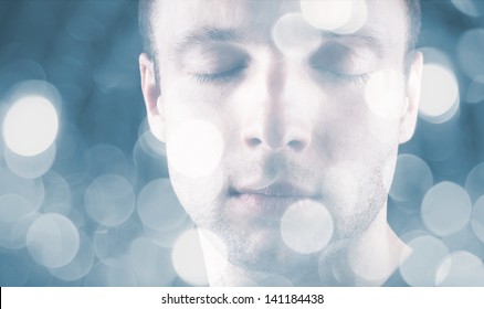 Sleeping young Caucasian man with closed eyes and blurred lights on blue background