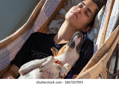 Sleeping with your pet. A brunette woman with curly sleeping in a hammock with her female dog. Animal world. Pet lover. Animals defenders. Dog lover.