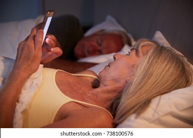 Sleepless Senior Woman In Bed At Night Using Mobile Phone