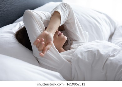 Sleepless young woman suffering from insomnia or nightmares close up, bad dreams, tired depressed female covering eyes with hands, lying on pillow in bed, feeling headache or migraine - Powered by Shutterstock