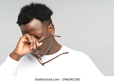 Sleepy African American man take off glasses rubbing his eyes feels tired after work on laptop computer isolated on grey background. Exhausted black male wants to sleep. Overwork, chronic fatigue eyes