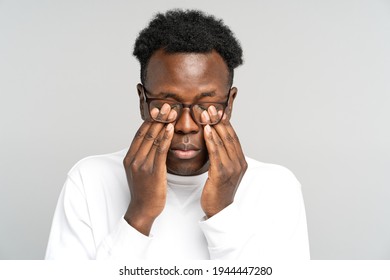 Sleepy African American man wear glasses rubbing his eyes, feels tired after work on laptop computer, isolated on grey background. Exhausted black male wants to sleep. Overwork, chronic fatigue eyes.