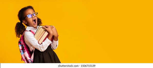 Sleepy Afro Elementary Student Girl Yawning Holding Heavy Books On Yellow Background. School Morning Routine Concept. Panorama, Free Space