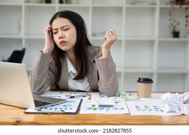 Sleepy Asian Businesswoman Yawning At Work In The Afternoon After Being Tired And Fed Up With Working With Laptop And Financial Graph Documents At Work.