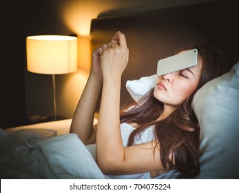 Sleepy Asian Woman In White Bed, Dropped Smart Phone On Face