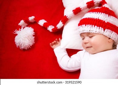 Sleepy Baby On Red Blanket In Knitted Hat