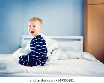 Sleepy Boy Sitting In Bed And Crying. Tired Child In Bedroom