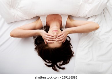 Sleepy brunette woman waking up and rubbing her eyes.