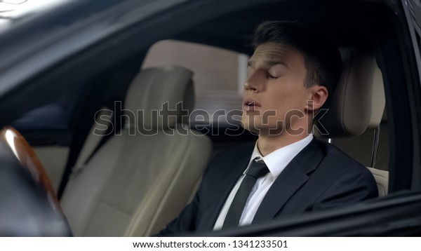 Sleepy business person sitting in car, sleeping\
disorder, stressful\
lifestyle