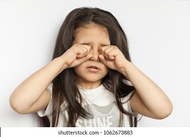 Sleepy child girl rubs her eyes on white background - Powered by Shutterstock