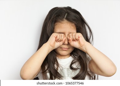 Sleepy Child Girl Rubs Her Eyes On White Background