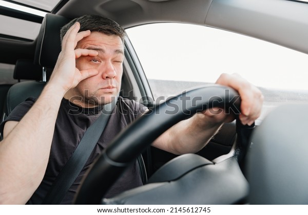 a\
sleepy man with closing eyes drives a car on the highway. car\
journey. driving school. fatigue from a long road trip\
