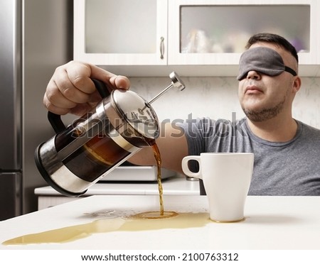 Sleepy man falls asleep at the kitchen table during breakfast and pours coffee past the mug. person with spilled coffee in morning. Drowsy male waking up and pouring tea. wake up, lack of sleep