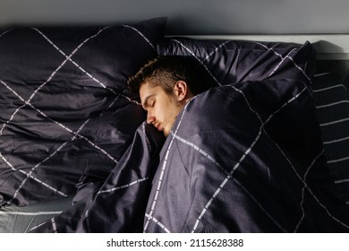 A sleepy man sleeping on tight in his cozy bed