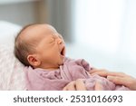 Sleepy newborn baby boy yawn at home 