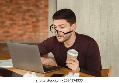 Sleepy Overworked Man At Laptop Holding Coffee Cup Trying To Work Sitting In Modern Office. Selective Focus - Powered by Shutterstock