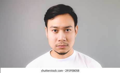 A Sleepy Straight Face. An Asian Man With White T-shirt And Grey Background.