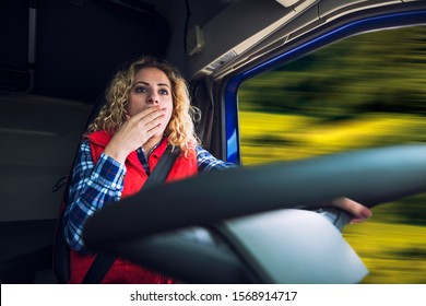 Sleepy and tired truck driver driving truck. Woman female trucker yawning due to tiredness and boredom while steering.
