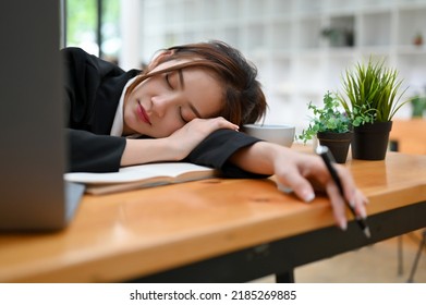 Sleepy and tired young Asian businesswoman or female offie worker taking nap or sleep on her office desk.