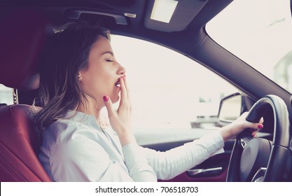 Sleepy woman driving her car after long hour trip isolated street background. Sleep deprivation and accident concept