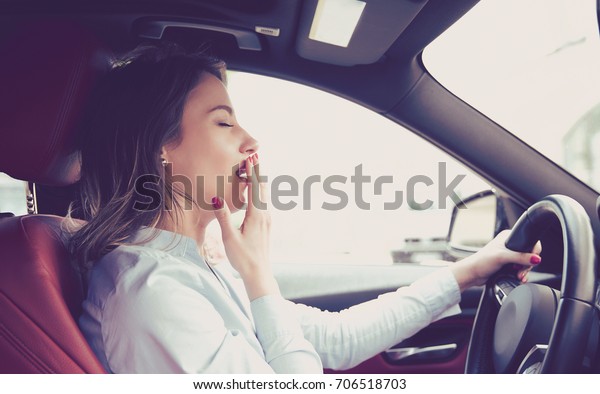 Sleepy\
woman driving her car after long hour trip isolated street\
background. Sleep deprivation and accident\
concept