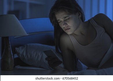 The Sleepy Woman Lay With A Phone On The Bed. Night Time