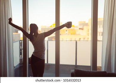 Sleepy woman stretching,drinking a coffee to wake up early in the monday morning sunrise.Starting your day.Wellbeing.Positive energy,productivity,happiness,enjoyment concept.Morning ritual - Powered by Shutterstock