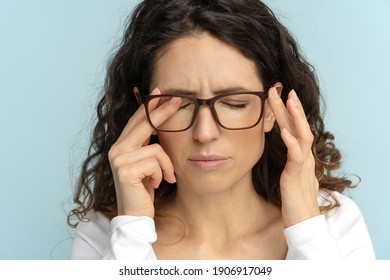 Sleepy young caucasian business woman in glasses rubbing eyes, feels tired after working on laptop, isolated on blue background. Exhausted office employee suffering from ocular diseases, eye strain.