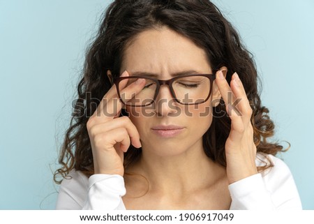 Sleepy young caucasian business woman in glasses rubbing eyes, feels tired after working on laptop, isolated on blue background. Exhausted office employee suffering from ocular diseases, eye strain. Stok fotoğraf © 