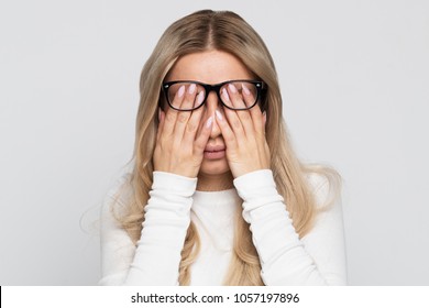 Sleepy young caucasian businesswoman in eyeglasses rubbing her eyes, feels tired after working on laptop, isolated on grey background.Overwork, tired, health concept.Exhausted, fatigue eyes
