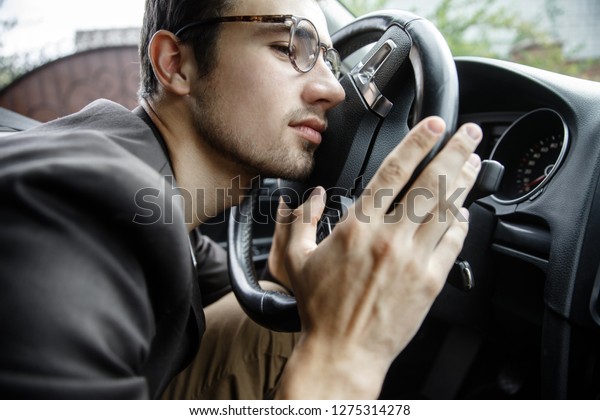 Sleepy young guy\
leans his head on the steering wheel. His hands are on the steering\
wheel. Road safety\
concept.