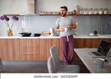 Sleepy young guy yawns while prepare coffee at the morning. - Powered by Shutterstock