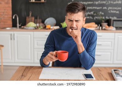 Sleepy Young Man With Cup Of Hot Coffee In Kitchen