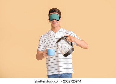 Sleepy Young Man Pouring Water From Electric Kettle In Cup On Color Background