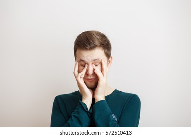 Sleepy Young Man Rubbing Eyes On A Light Background