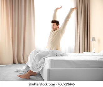 Sleepy Young Man Stretching On Bed.