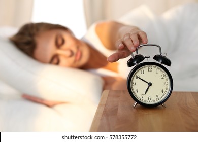 Sleepy Young Woman Stretching Hand To Ringing Alarm To Turn It Off. Early Wake Up, Not Getting Enough Sleep, Getting Work Concept. 