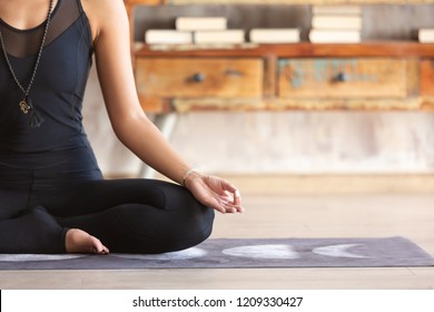 Slender asian yoga girl wearing black sportswear sitting in Lotus pose close up. Peaceful girl sitting in ardha Padmasana. Practicing yoga at home on mat. No stress, freedom, meditating concept. - Powered by Shutterstock